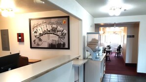 A hotel lobby with a reception desk, a framed welcome sign, a coffee machine, and a seating area with tables and chairs. - Hotel Hamilton (Hamilton)