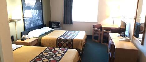 A hotel room with two beds, a desk, a chair, a TV, and a window with curtains.