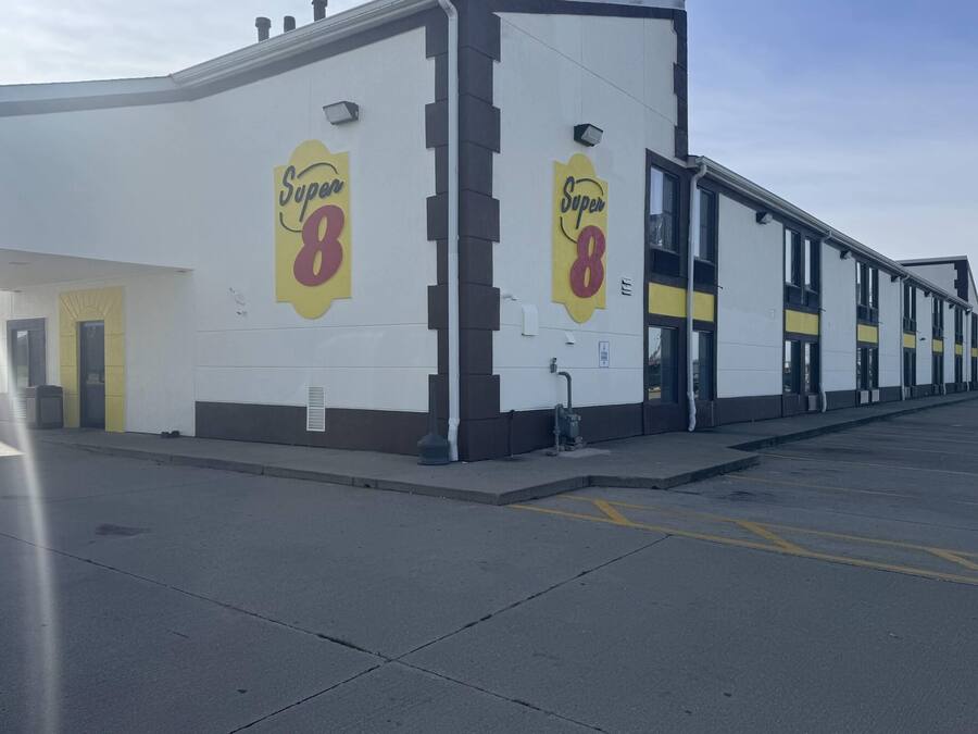 A Super 8 hotel with a white facade, multiple doors, and a parking lot.
