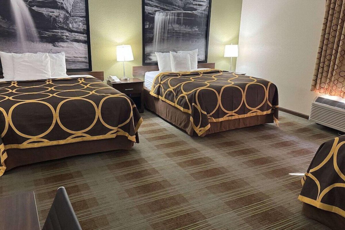 A hotel room with two beds, a check-in desk, and a large window with curtains.
