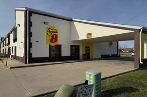 Un motel Super 8 con un letrero amarillo, un aviso de altura máxima y un letrero que advierte que los vehículos no autorizados serán remolcados.