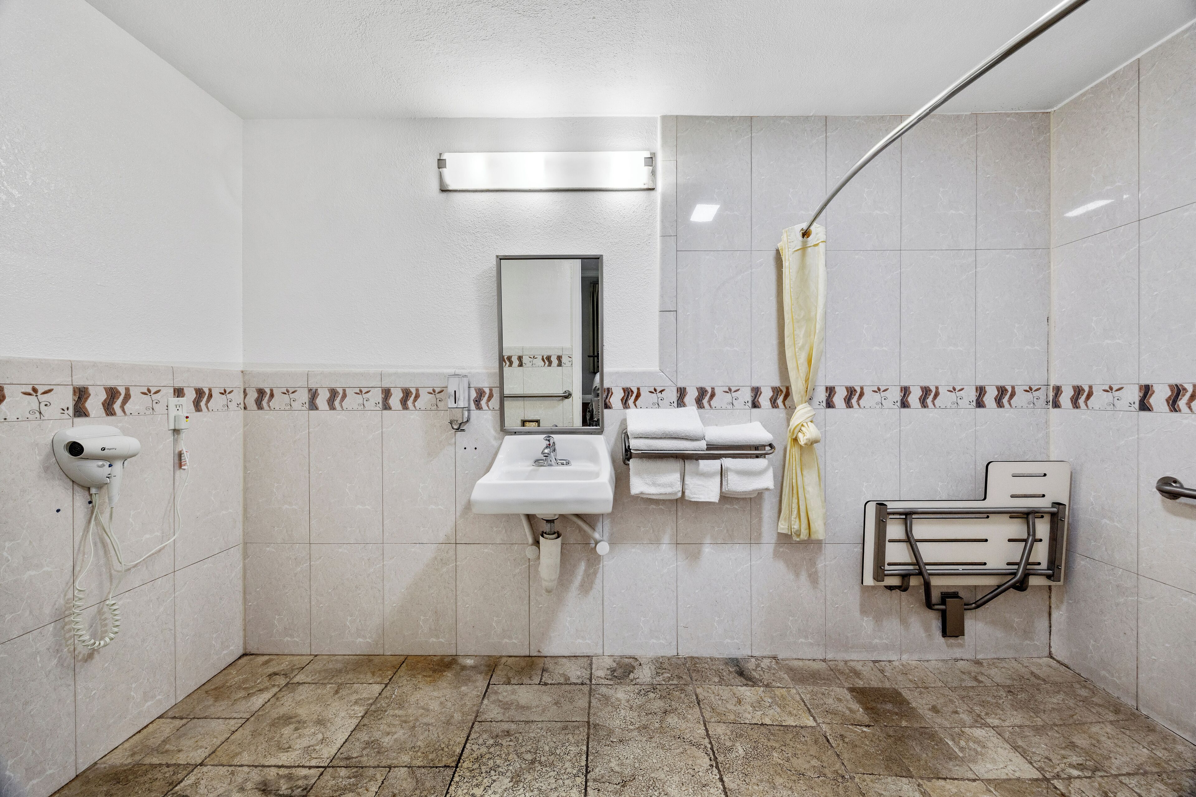 Un baño con lavamanos, espejo, toallero y cortina de ducha.
