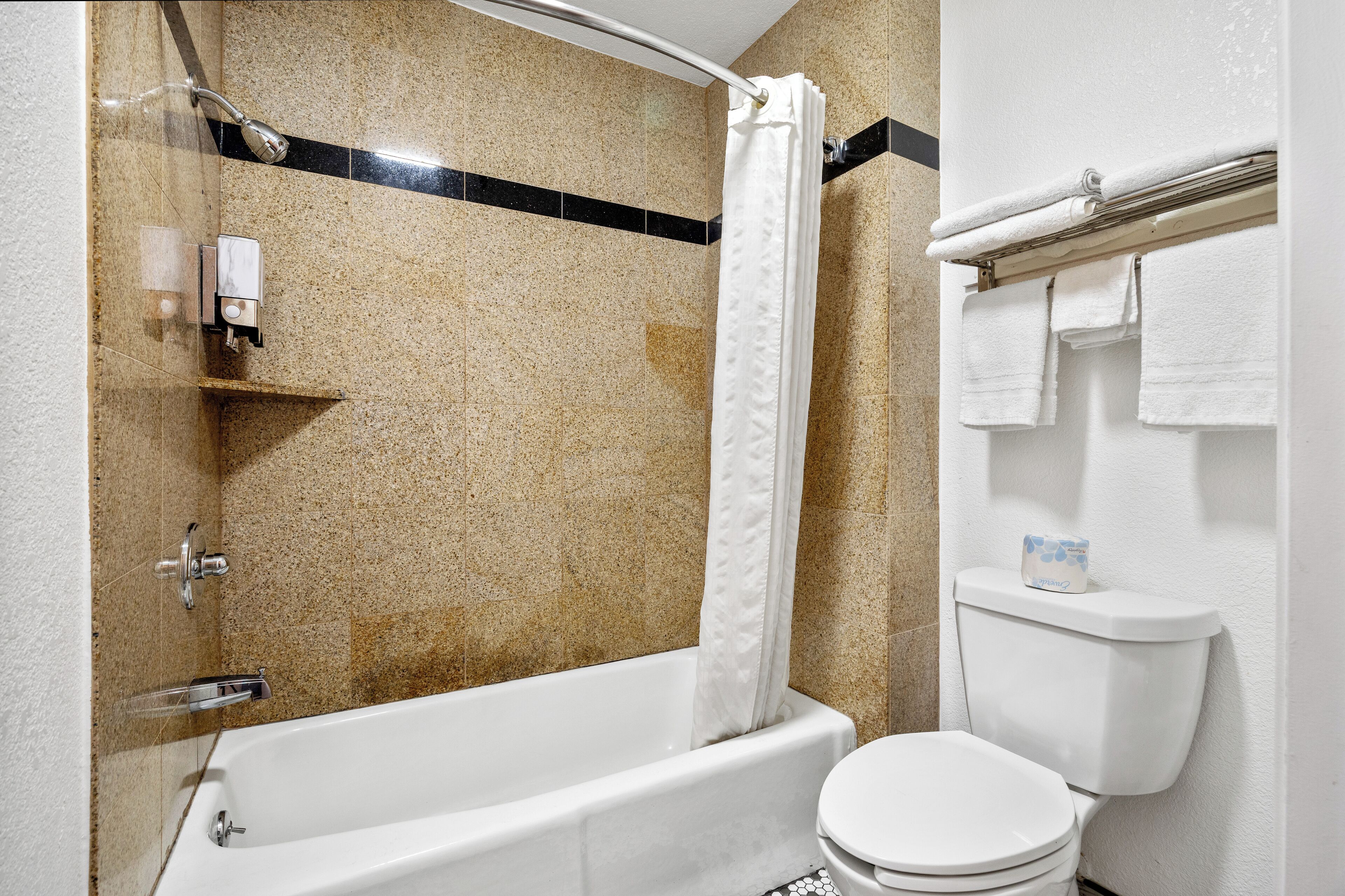 A bathroom with a bathtub, toilet, and shower curtain.