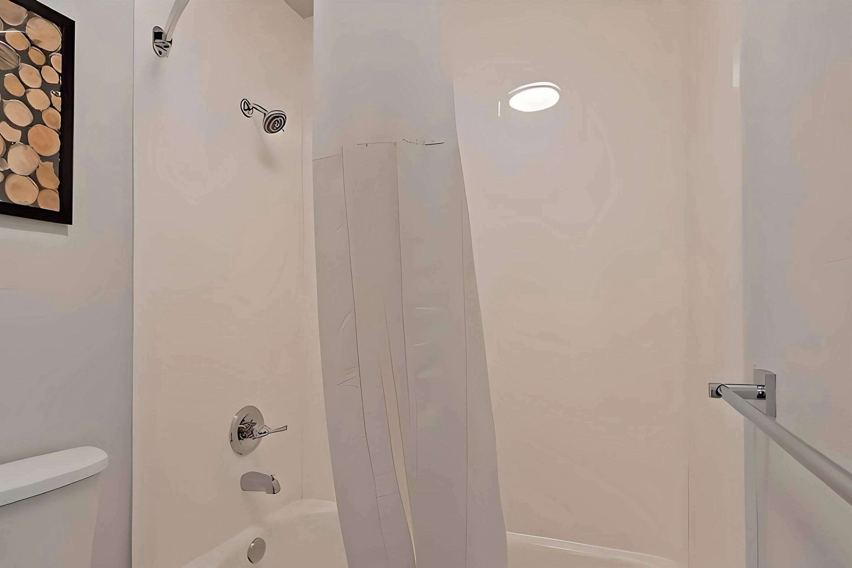 Een moderne badkamer met een douche, toilet en een kunstwerk in een lijst aan de muur.