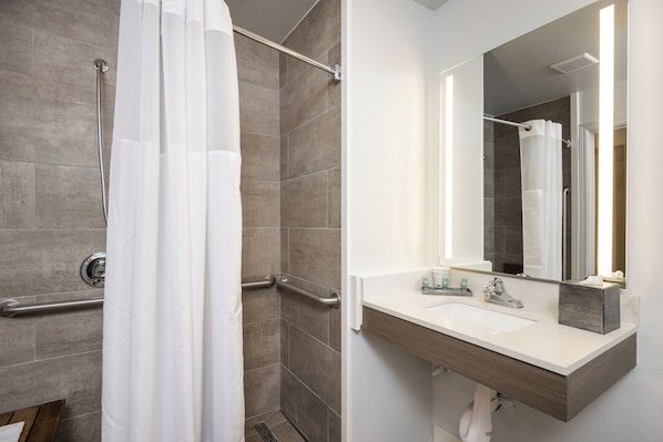 A modern bathroom with a shower, grab bars, a sink, and a mirror. - Comfort Inn Hayward - Oakland South (Hayward)