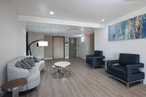 A modern hotel lobby with a curved sofa, a round table, and two armchairs.