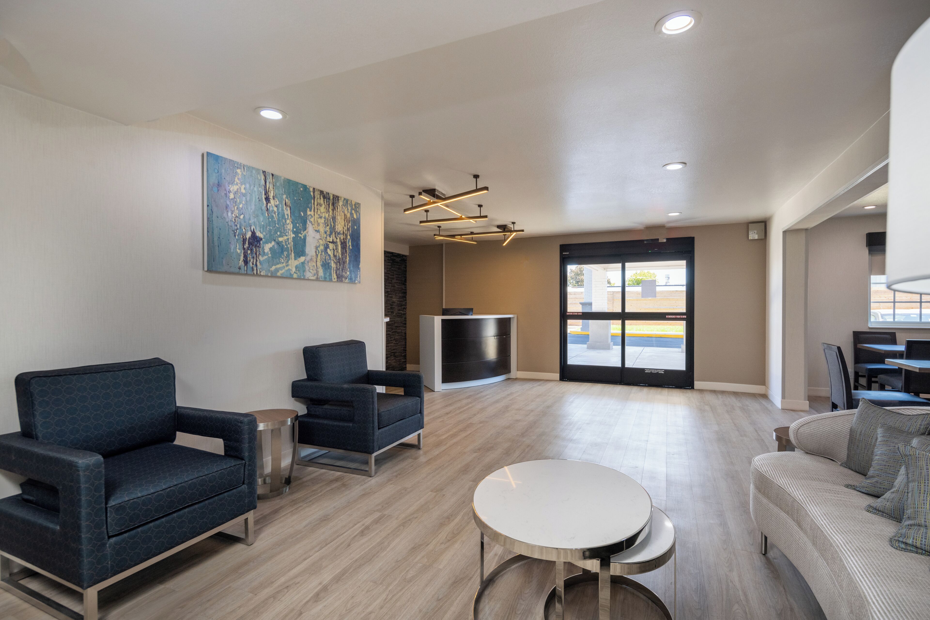 A modern lobby with seating areas, a reception desk, and a large window.