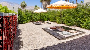 Un espace extérieur aménagé avec des tables et des bancs en bois, entouré de verdure et de palmiers.