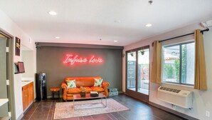 Un salon moderne avec un néon, un canapé, une table basse et une grande fenêtre.
