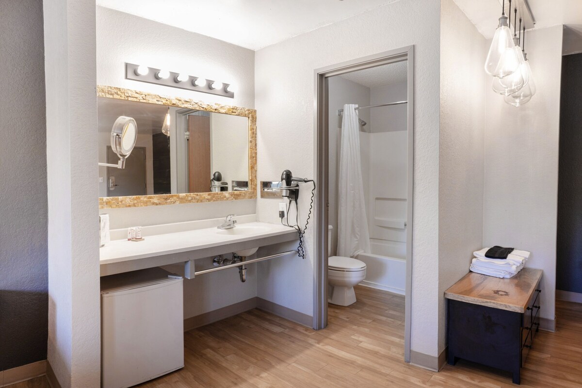 A modern bathroom with a vanity, mirror, and shower.