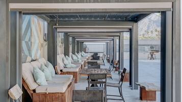 Un espacio al aire libre con mesas y bancos de madera, algunos con cojines.