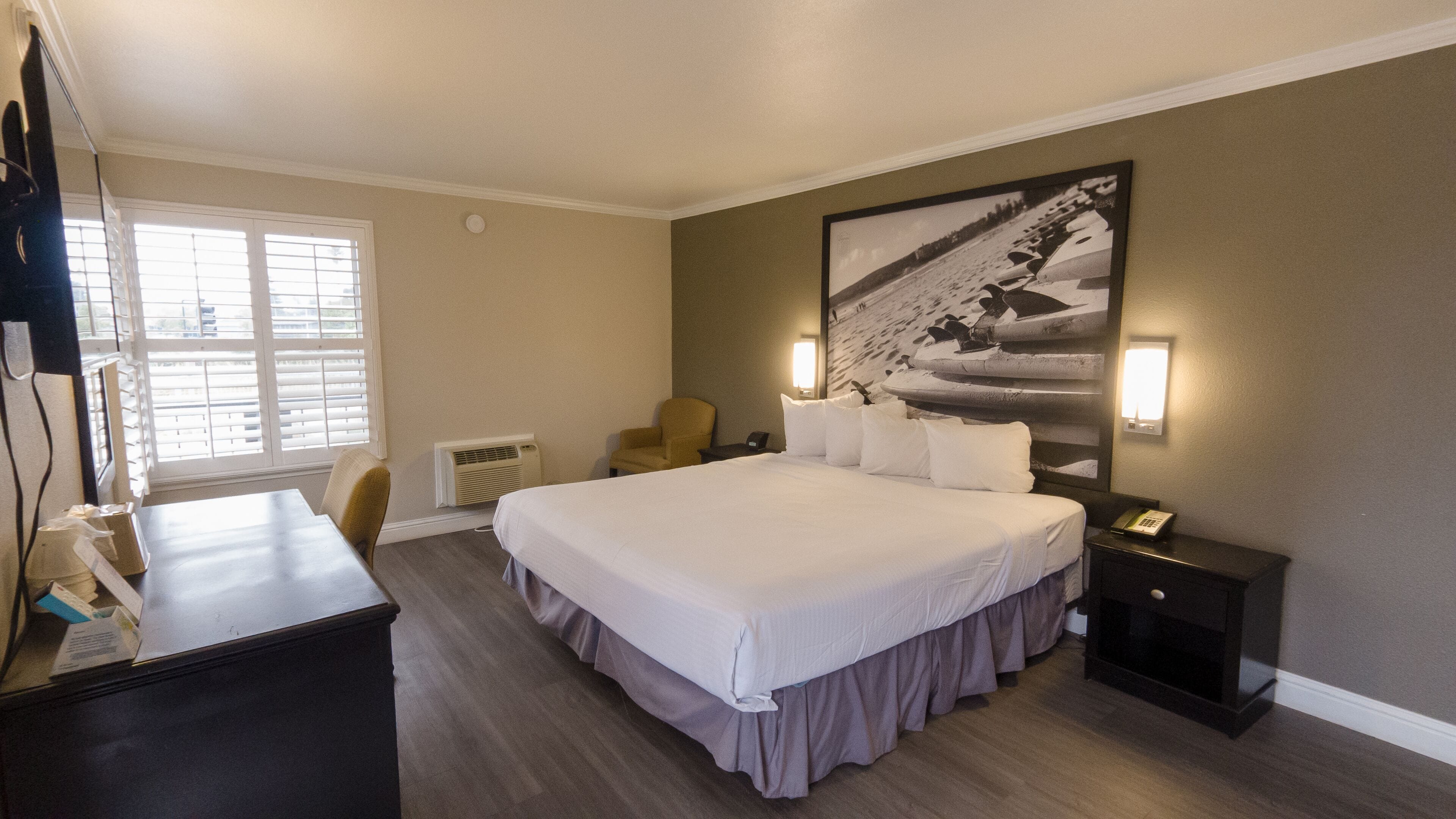 Une chambre d’hôtel avec un grand lit, un bureau, une chaise, un radiateur et un téléphone fixé au mur.