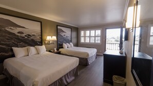 Habitación de hotel con dos camas, un escritorio, un cesto de basura y un ventanal con vistas.