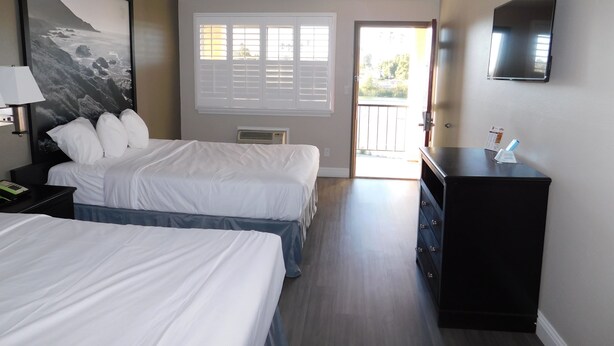 Habitación de hotel con dos camas, un cuadro grande, un televisor y vistas al exterior.