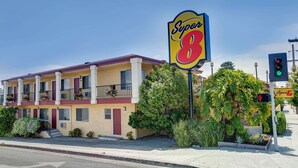 Un motel con un llamativo letrero de 'Super 8', una estructura de dos pisos con balcones y un jardín bien cuidado.