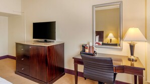 A hotel room with a wooden desk, a television on top, a mirror, and a lamp. - Inn at the Highland Denver Downtown (Denver)