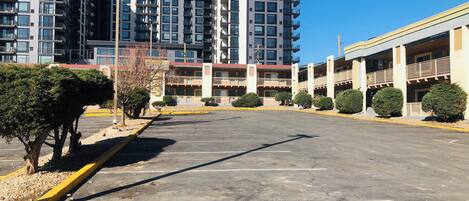 A parking lot with a bicycle symbol, surrounded by modern buildings with multiple floors and balconies.