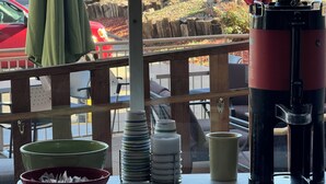 A table with a coffee maker, a stack of plates, a bowl, and a mug. - Inn at the Highland Denver Downtown (Denver)