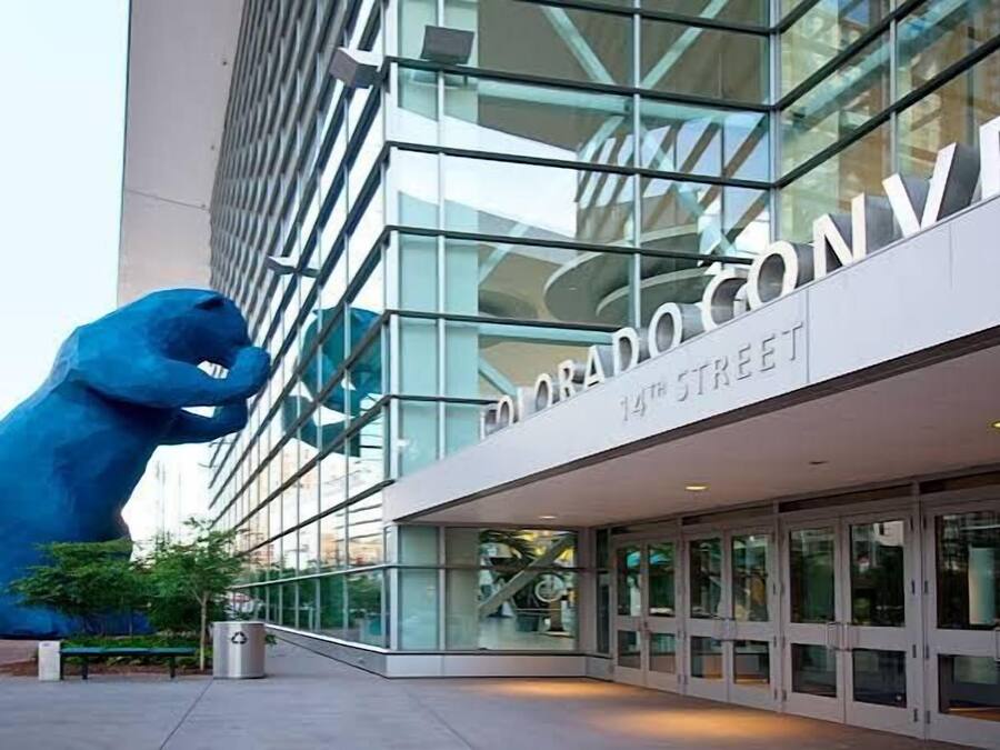 Un edificio moderno con fachada de vidrio y una gran escultura azul en primer plano.