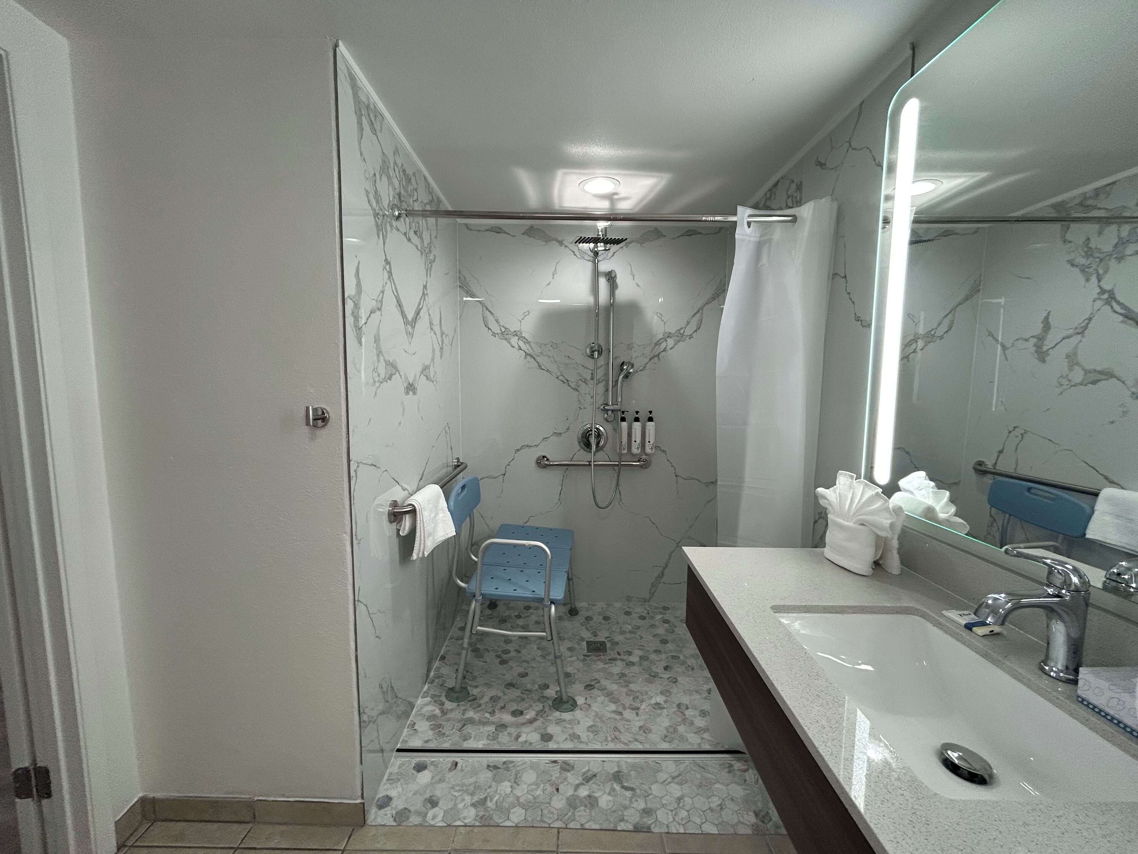 Une salle de bain moderne avec une douche à parois de verre, un meuble-lavabo et un miroir.