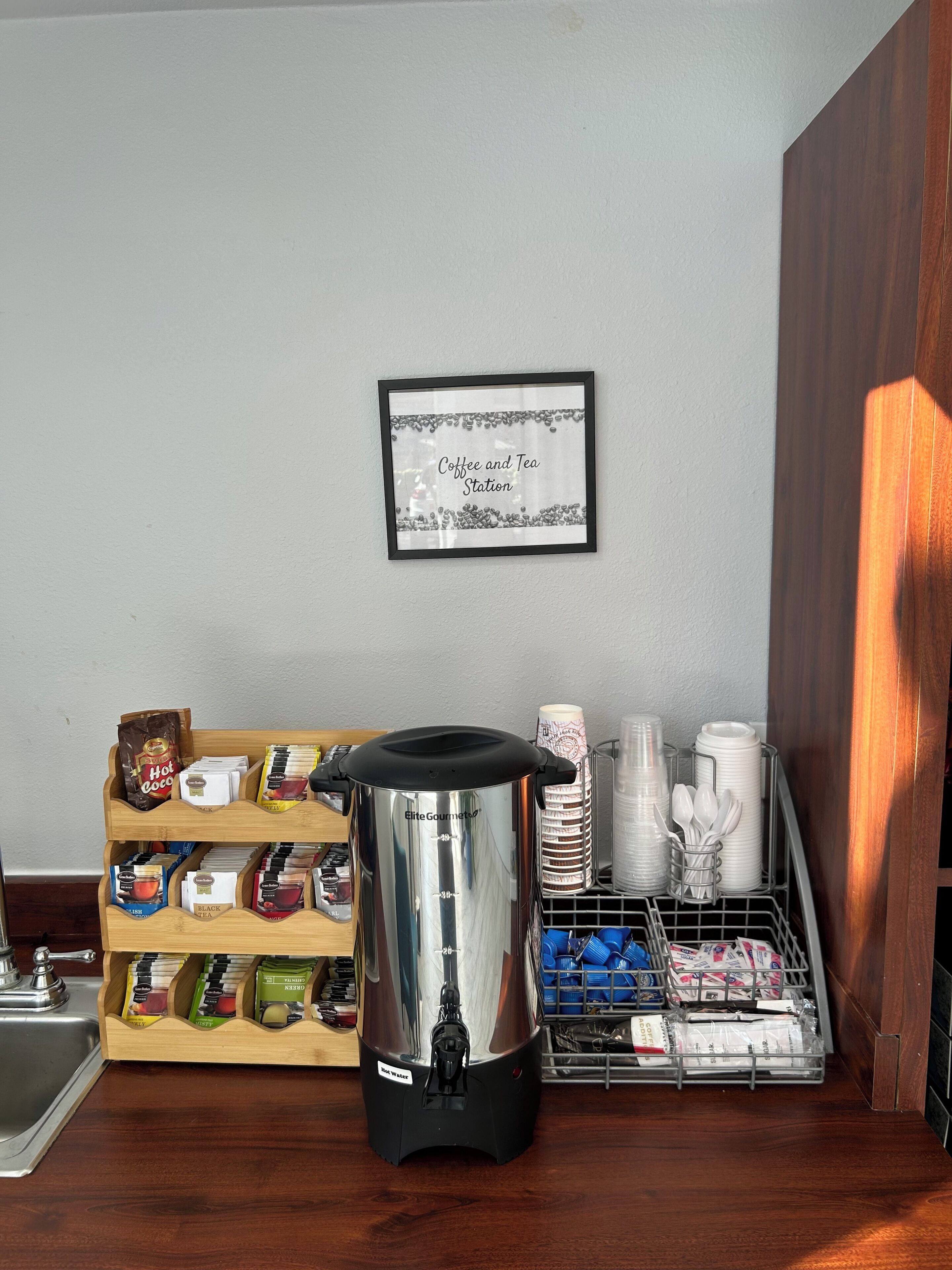 Una estación de café con dispensador de agua caliente, cápsulas de café y bolsitas de té.