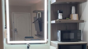 A modern bathroom with a large mirror, a sink, a microwave, and a refrigerator. - Mission Inn San Luis Obispo (San Luis Obispo)