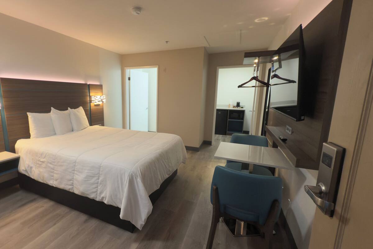 Una camera d'albergo con un letto grande, una scrivania, una sedia, una televisione e un armadio.
