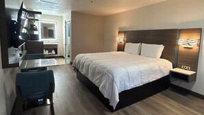 A hotel room with a bed, bedside table, and a desk with a chair. - Mission Inn San Luis Obispo (San Luis Obispo)