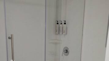 A modern bathroom with a glass-enclosed shower, a toilet, and a towel rack.