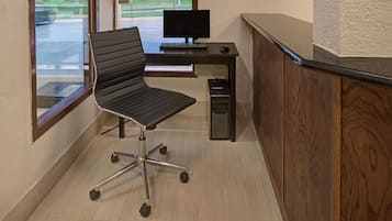 A modern office space with a black office chair, a desk with a computer, and a small cabinet.