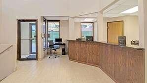 A reception area with a wooden reception desk, a computer, and a chair.