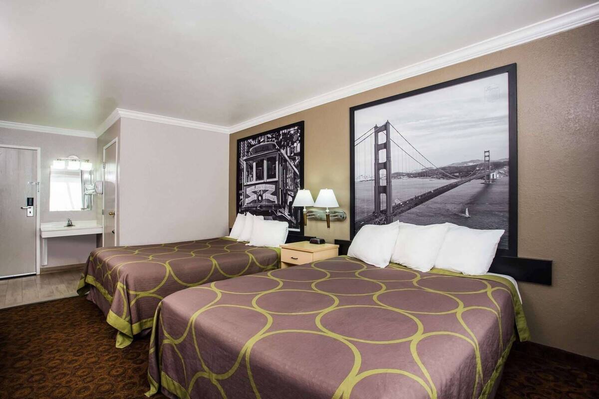 A hotel room with two beds, a bathroom, and a large window with a view of a bridge.