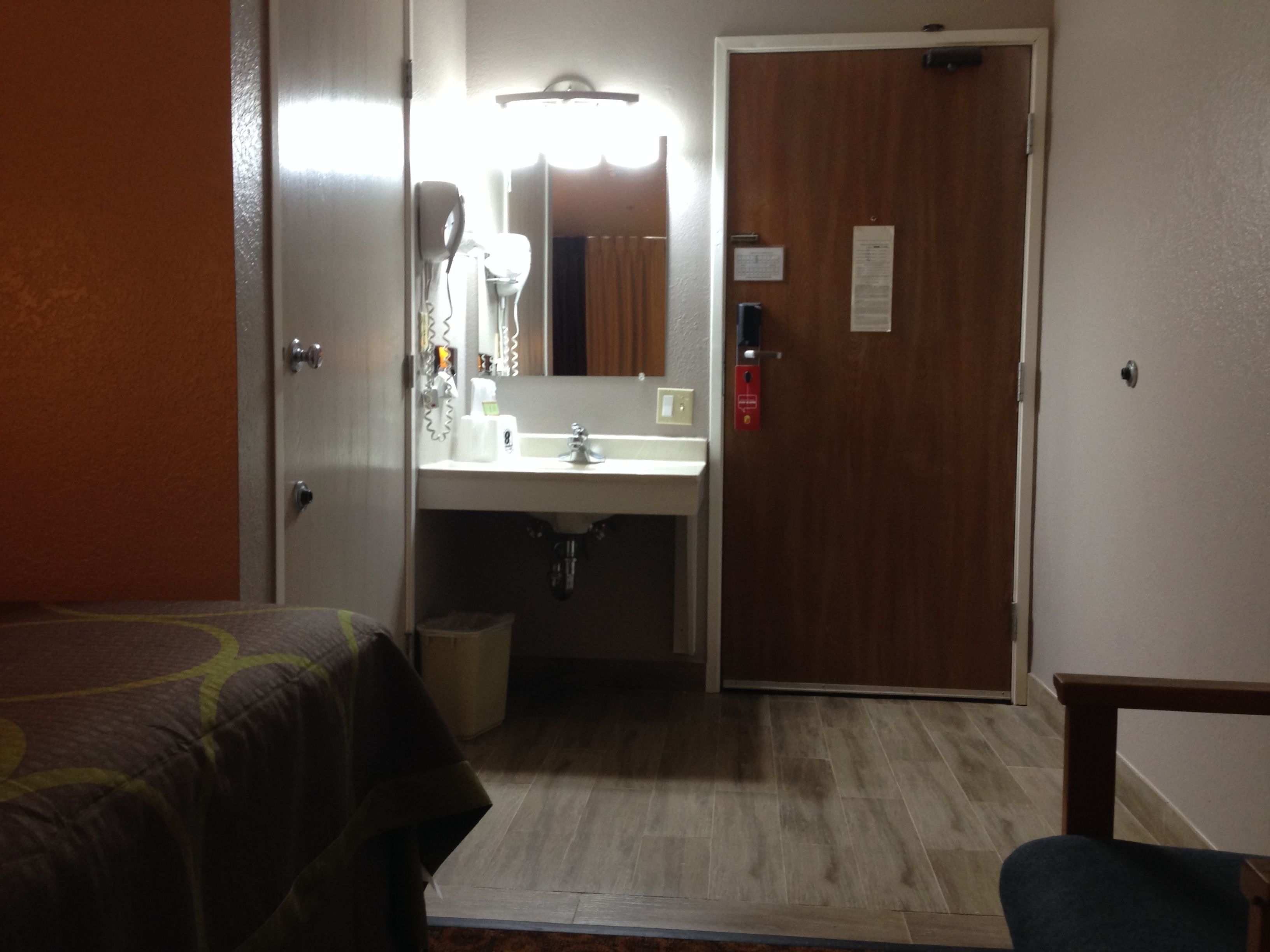 A hotel room with a bed, a bathroom with a sink, and a mirror.