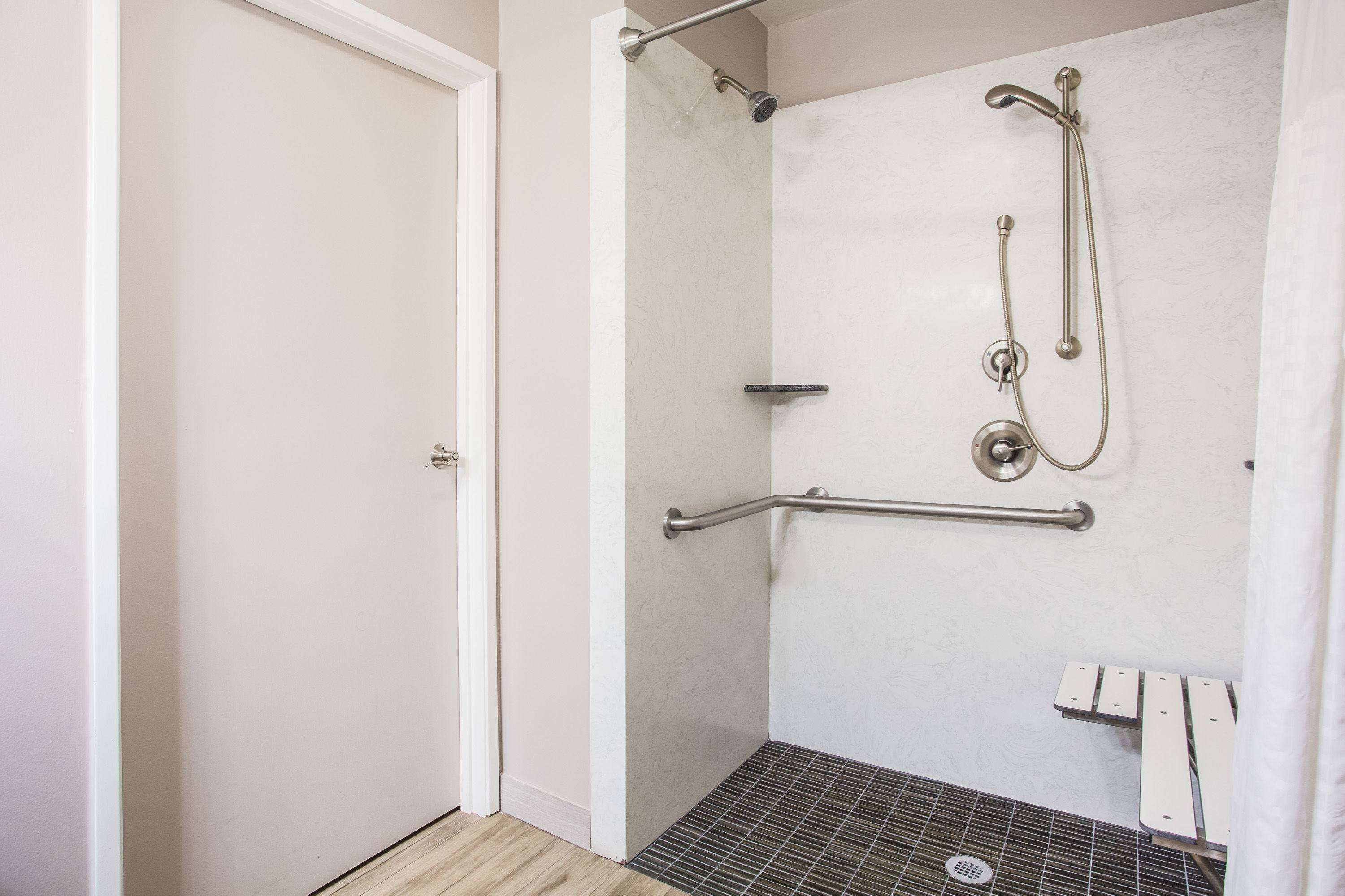 A shower with a handheld showerhead, a handheld showerhead, and a handheld showerhead.