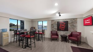 A spacious room with a dining area, a seating area, and a wall-mounted TV. - Red Roof Inn Mansfield (Mansfield)