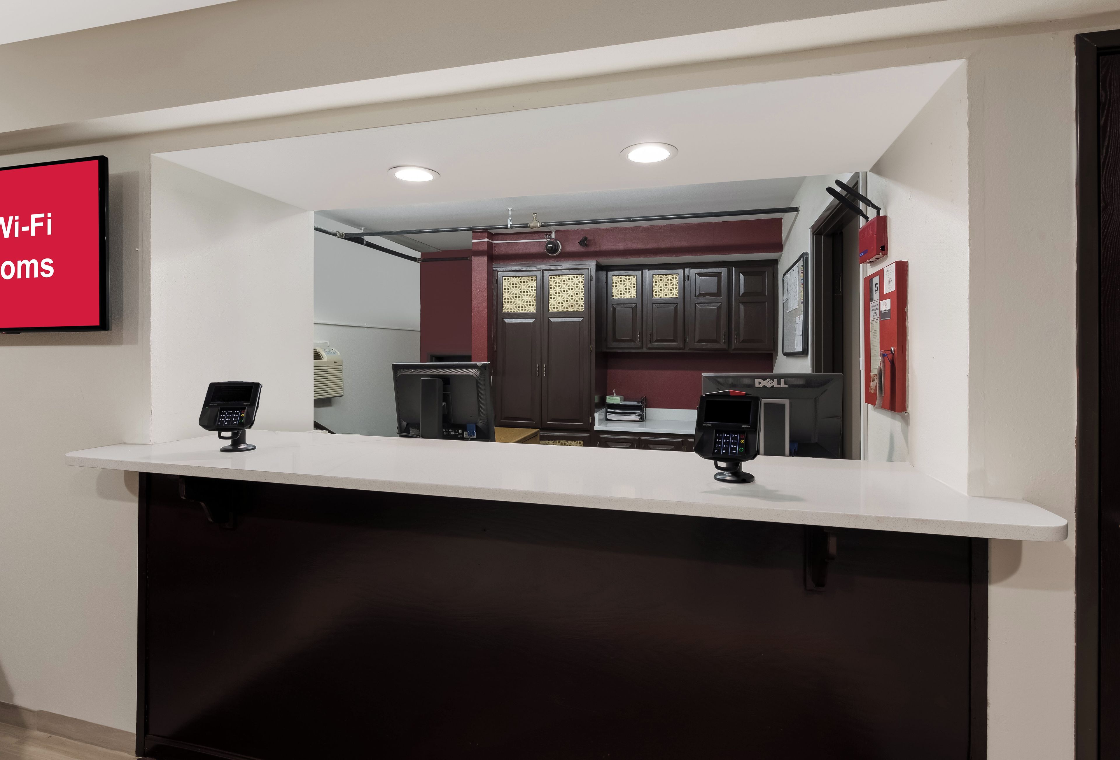 A reception desk with two card readers, a fire alarm, and a bulletin board.