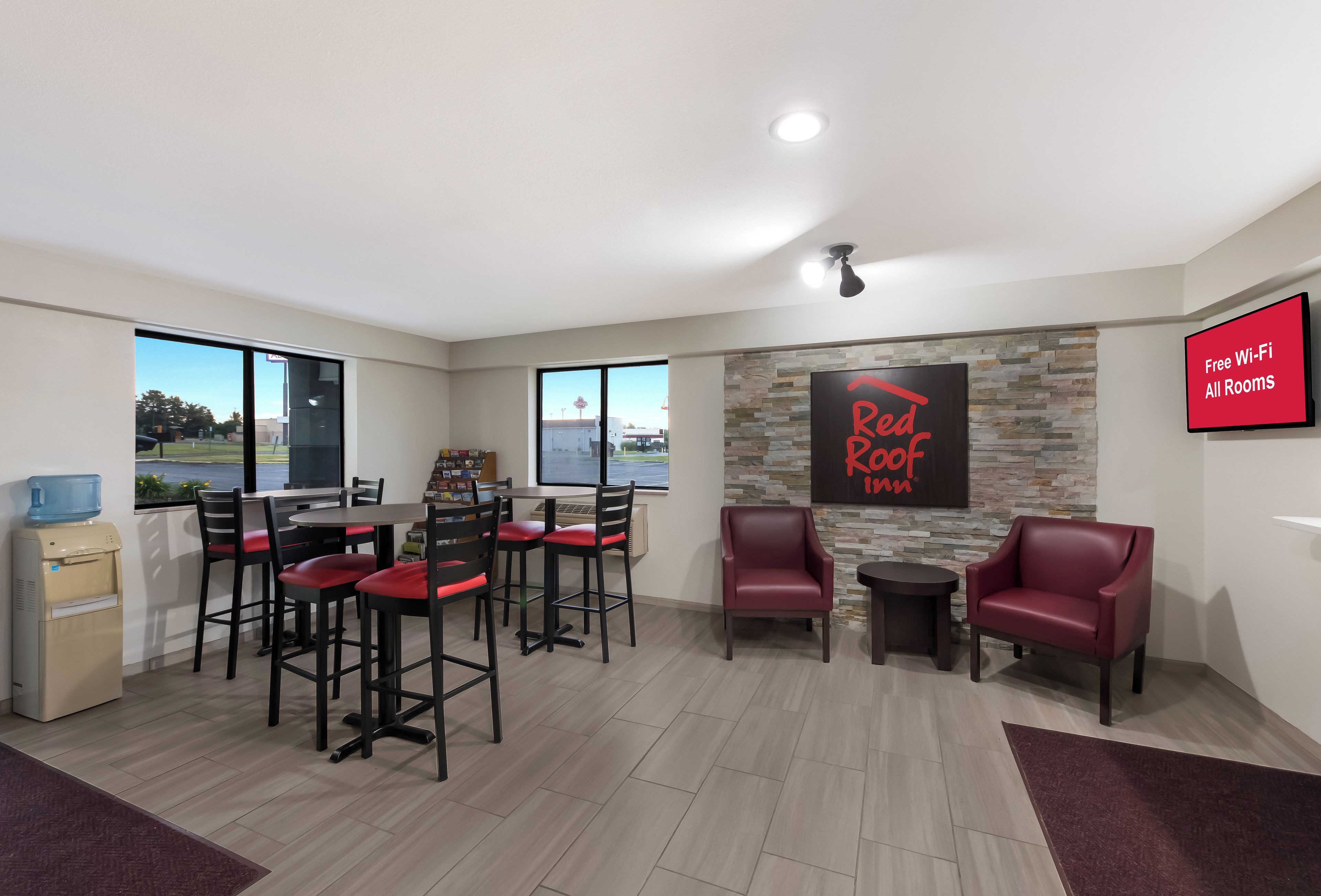 A room with a dining area, a water cooler, a stone wall, and a sign indicating free Wi-Fi.