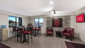 Una habitación con zona de comedor, dispensador de agua, pared de piedra y un cartel que indica Wi-Fi gratuito.