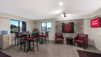 A room with a dining area, a water cooler, a stone wall, and a sign indicating free Wi-Fi.