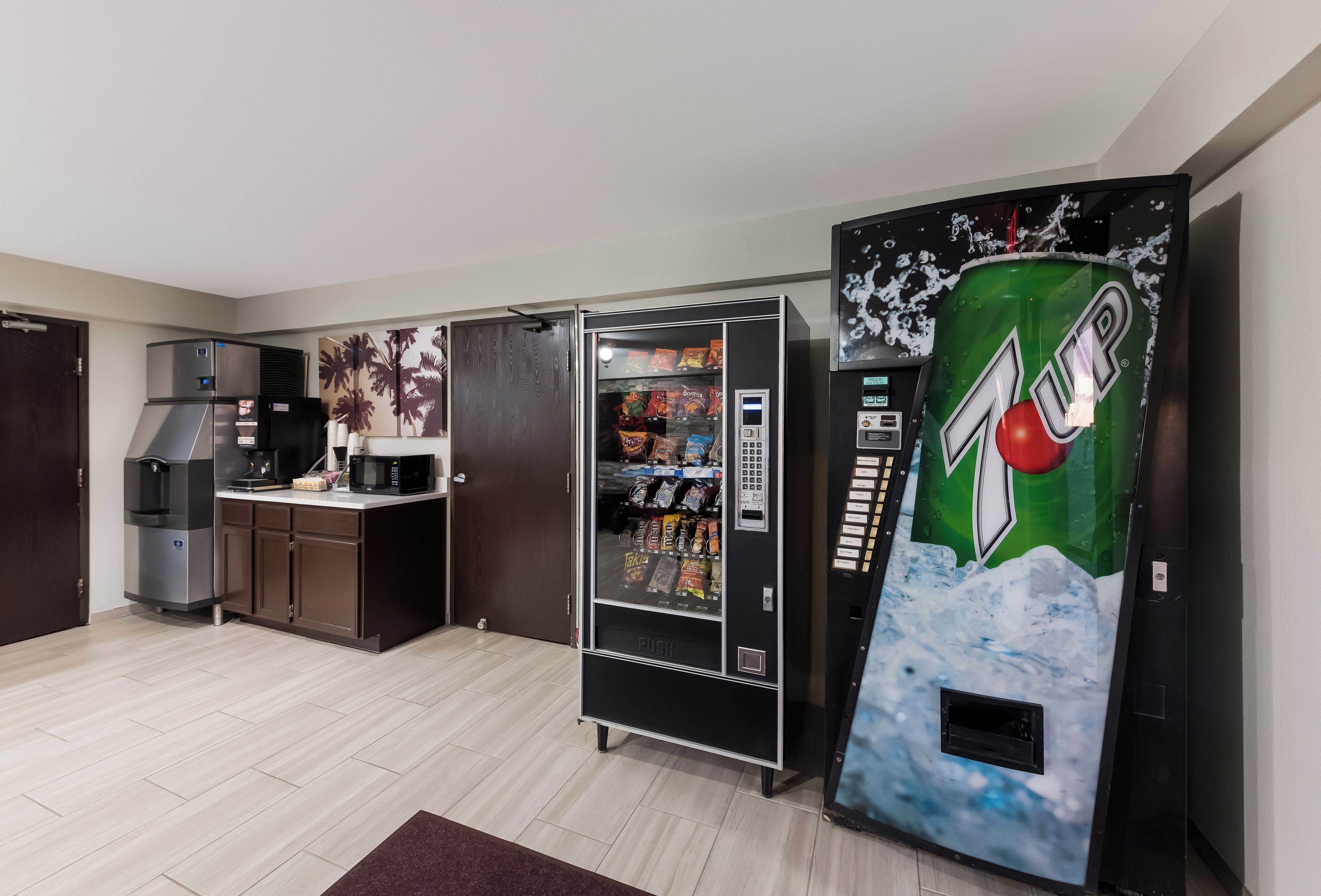 Een kitchenette met een koelkast, magnetron en een automaat voor 7UP.