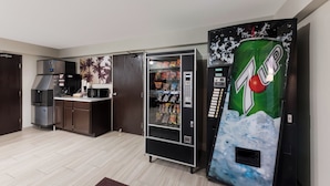 Una kitchenette con refrigerador, microondas y una máquina expendedora de 7UP.