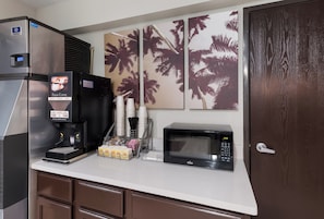 A kitchenette with a coffee machine, microwave, and a refrigerator.