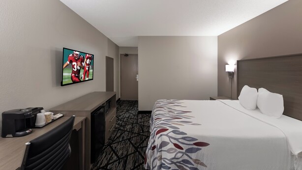 Habitación de hotel con cama, escritorio, televisor y cafetera.