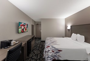 Habitación de hotel con cama, escritorio, televisor y cafetera.