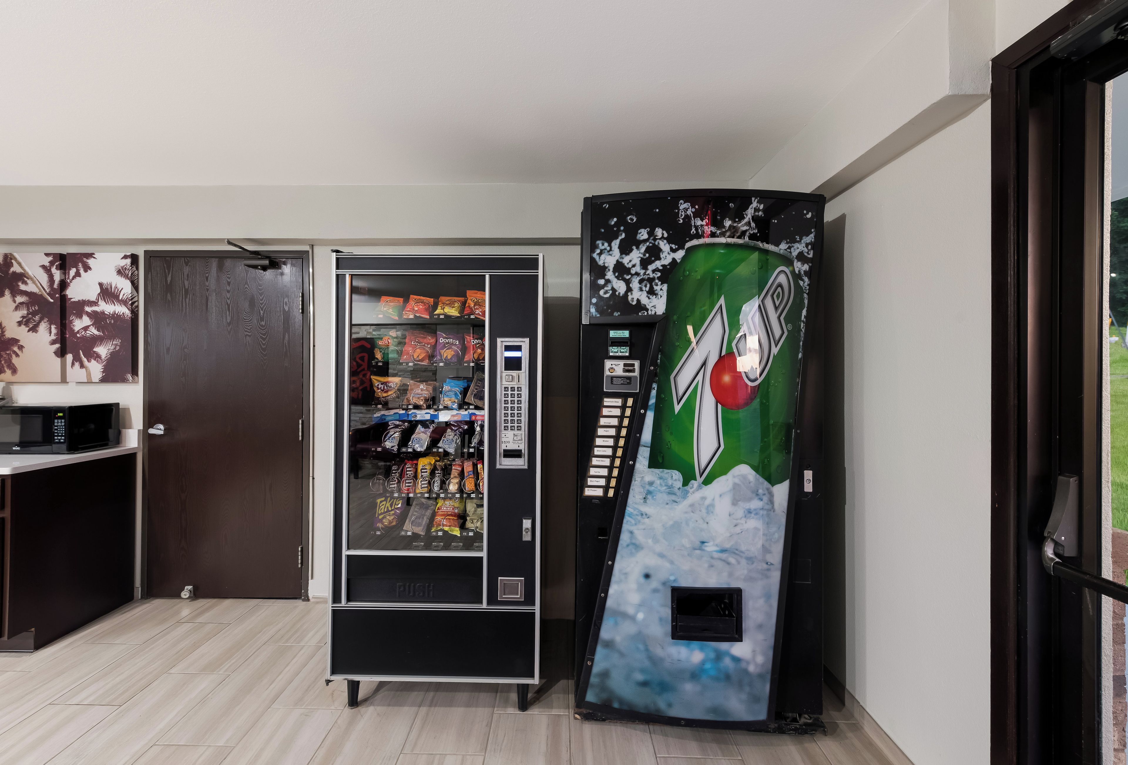 A vending machine with a Mountain Dew logo, a microwave, and a door with a wooden panel.