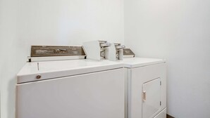 A white washing machine with a control panel and a dryer in a corner of a room.