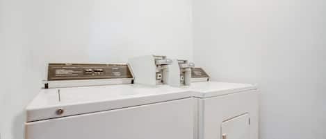 A white washing machine with a control panel and a dryer in a corner of a room.