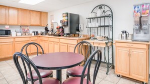 A kitchen with wooden cabinets, a coffee machine, a microwave, and a refrigerator.