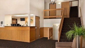 A reception area with a wooden desk, a staircase, and a seating area with a plant.