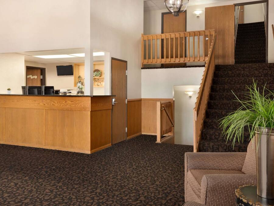 A reception area with a wooden desk, a staircase, and a seating area with a plant.